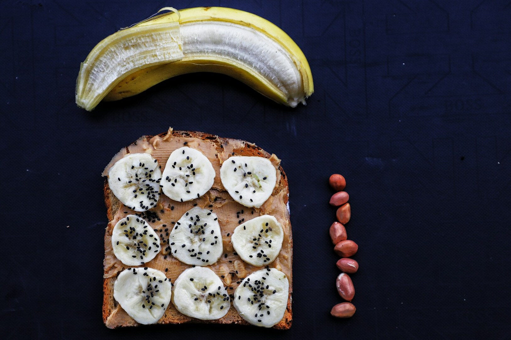 A creatively photographed banana and peanut butter sandwich resting on a sleek black table surface.