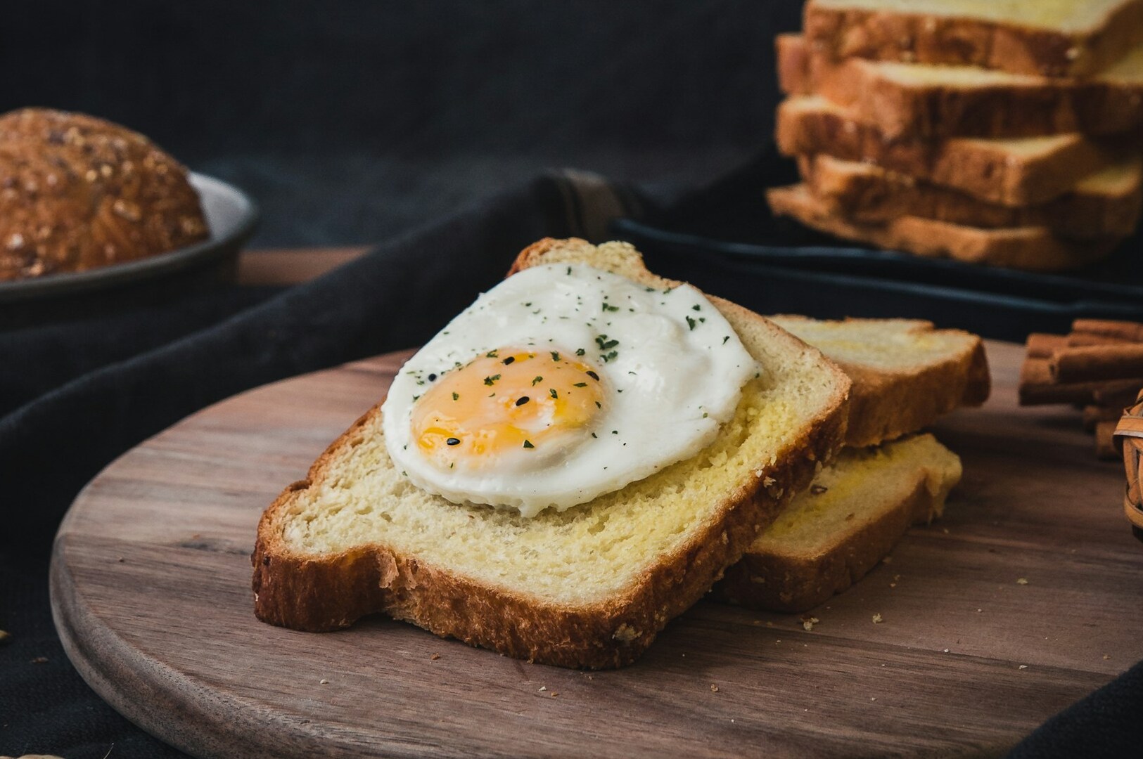 A perfectly fried egg atop golden toast, accompanied by cinnamon sticks, creating a cozy breakfast aesthetic.