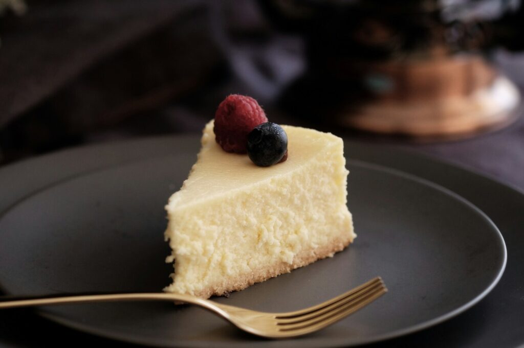 A piece of cheesecake served on a black plate with a fork, highlighting the art of food photography.