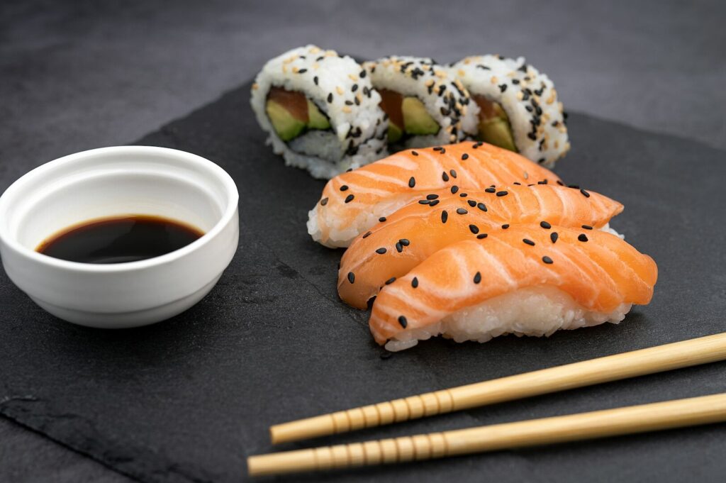 A close-up of sushi featuring salmon and chopsticks on a black slate, highlighting the elegance of food photography.