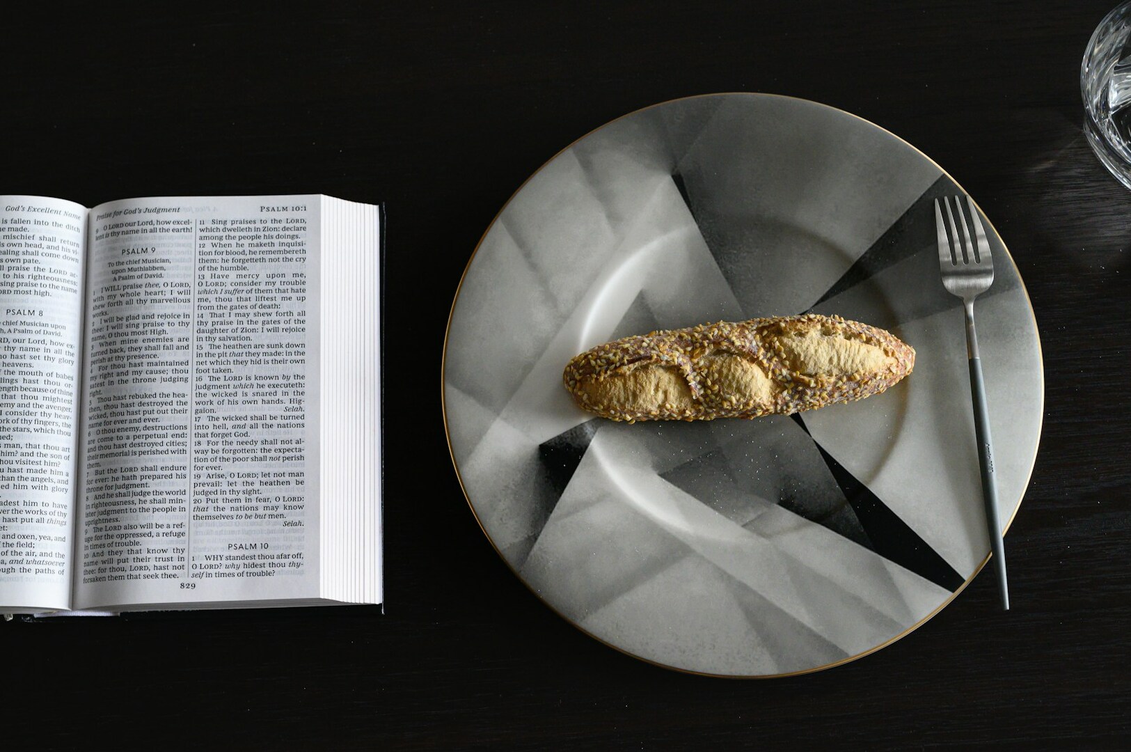 A rustic plate holding a loaf of bread next to a book, reflecting current food photography aesthetics.
