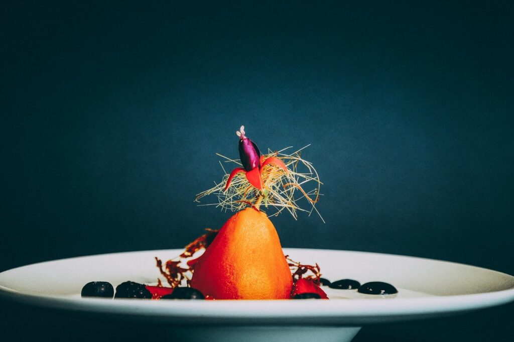 A dessert adorned with vibrant fruit and berries is presented on a white plate, reflecting the "Perfectly Imperfect" food photography.
