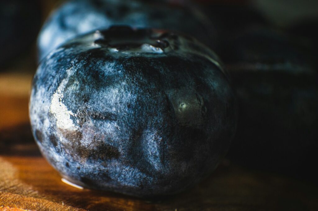A macro shot of plump blueberries arranged on a wooden cutting board, highlighting their rich color and detail.