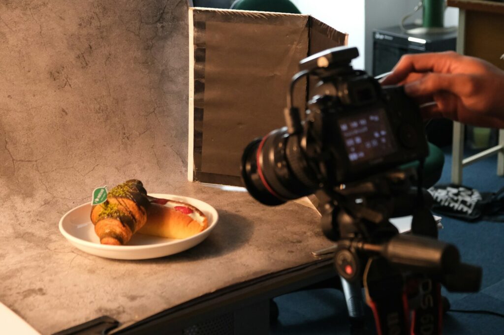 A hand holding a camera, focused on a colorful plate of food, showcasing the blend of culinary art and photography.