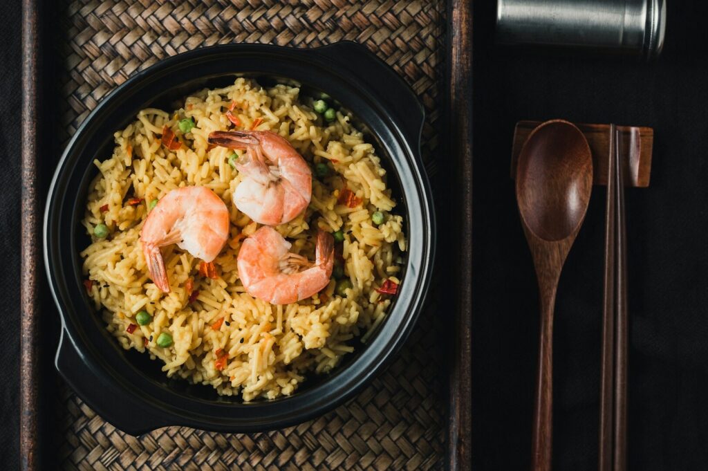 A bowl of fried rice with shrimp and vegetables, beautifully presented on a black background, highlighting Singaporean cuisine.