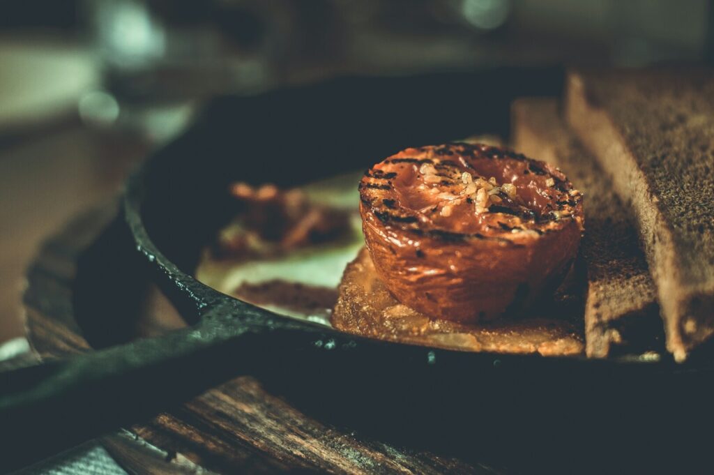 A close-up of a pan with crispy toast and a fresh tomato, highlighting Singaporean food photography.