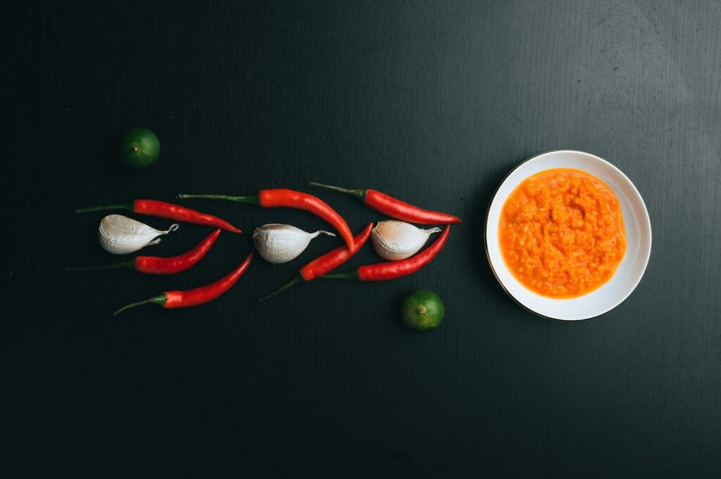 A bowl filled with chili sauce and garlic on a sleek black table, highlighting the essence of food photography in Singapore.