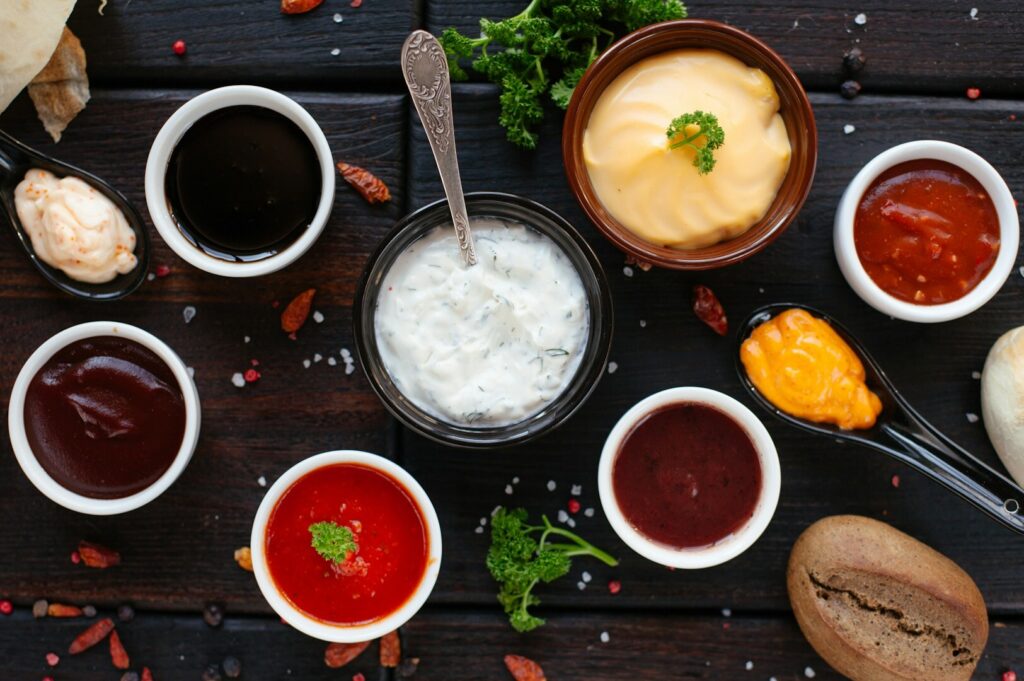 An overhead shot of an assortment of sauces and condiments arranged in bowls, highlighting their diverse colors and textures in a food photography style.