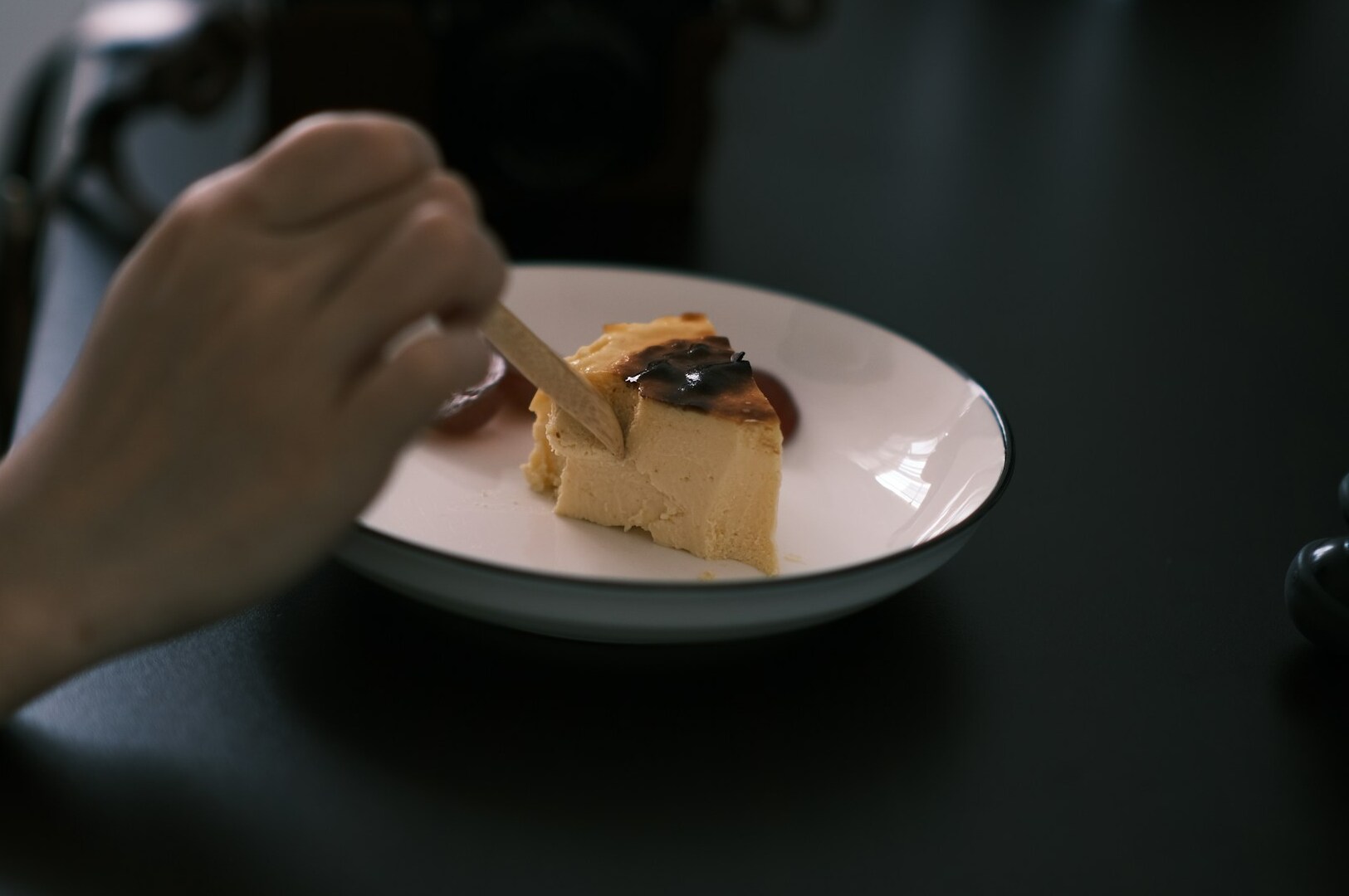 Close-up of a person savoring cheesecake on a plate, showcasing professional food photography techniques.