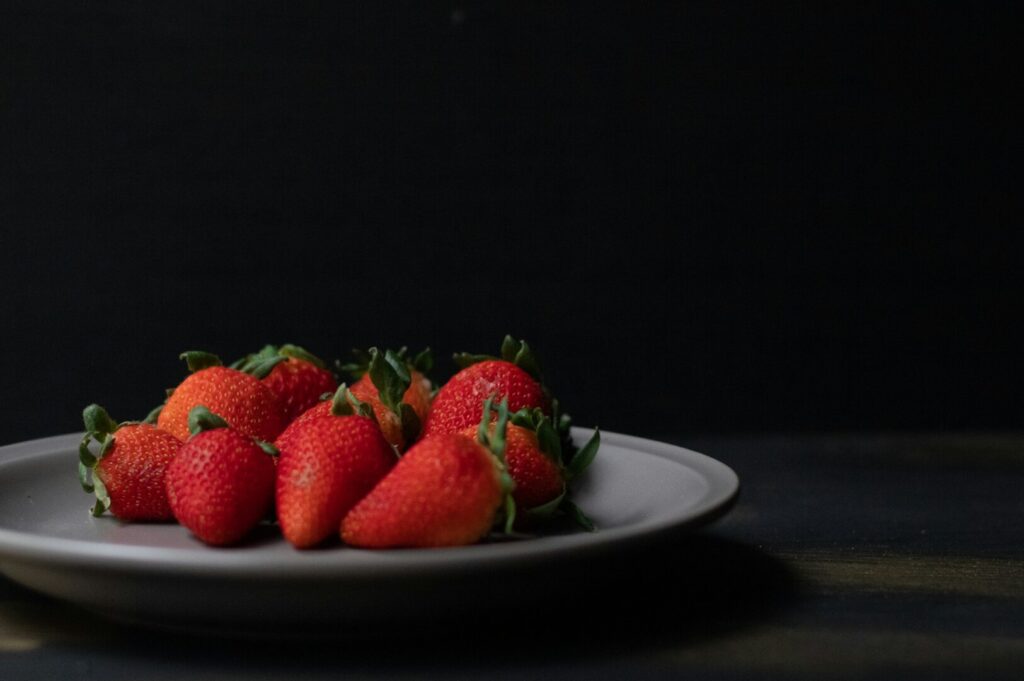 A plate of vibrant red strawberries, beautifully styled in a professional food photography setting.