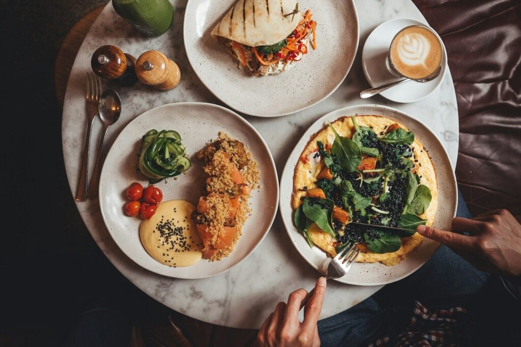 A person seated at a table, savoring a meal surrounded by an array of colorful dishes in a food photography setting.