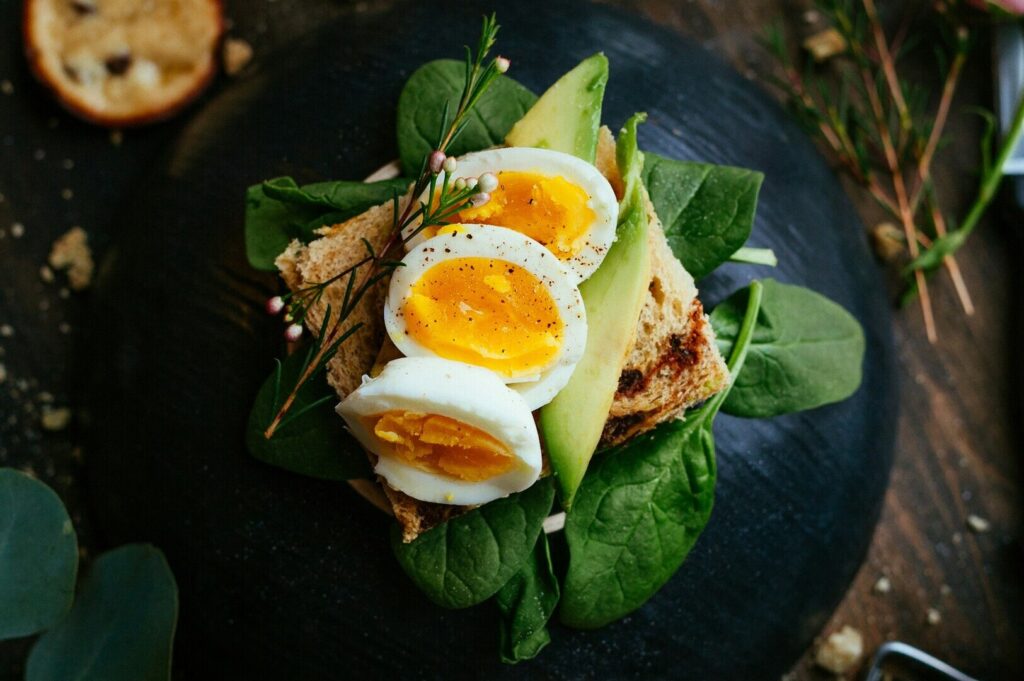 A beautifully arranged plate with an egg, creamy avocado, and fresh spinach, highlighting appetizing food photography.