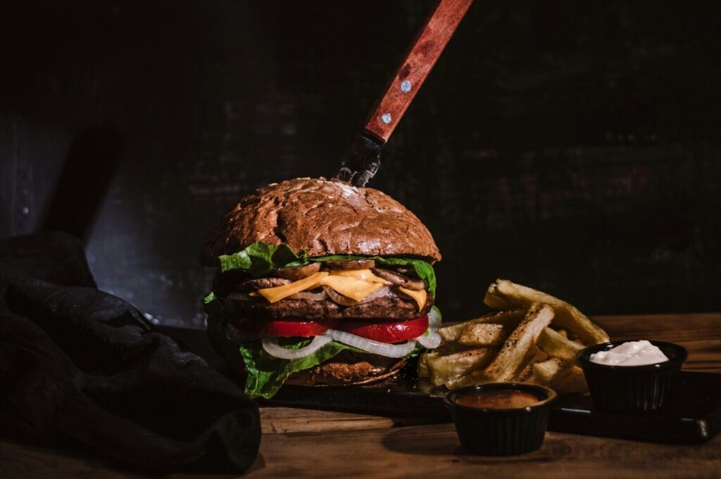 A delicious hamburger topped with cheese, lettuce, and tomato, presented on a wooden table in a food photography style.