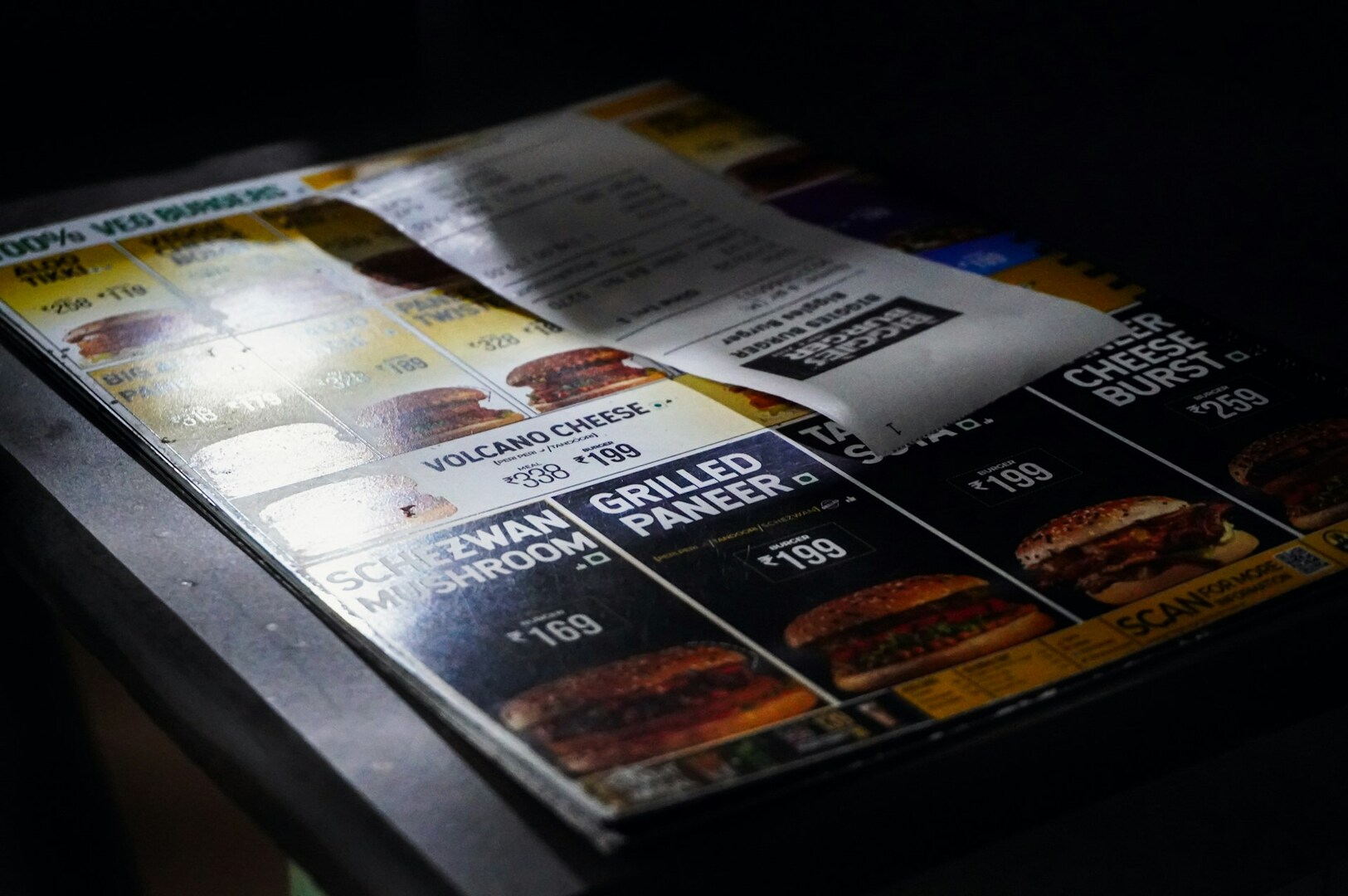 A menu displayed on a table alongside a receipt, showcasing food photography and menu design elements.