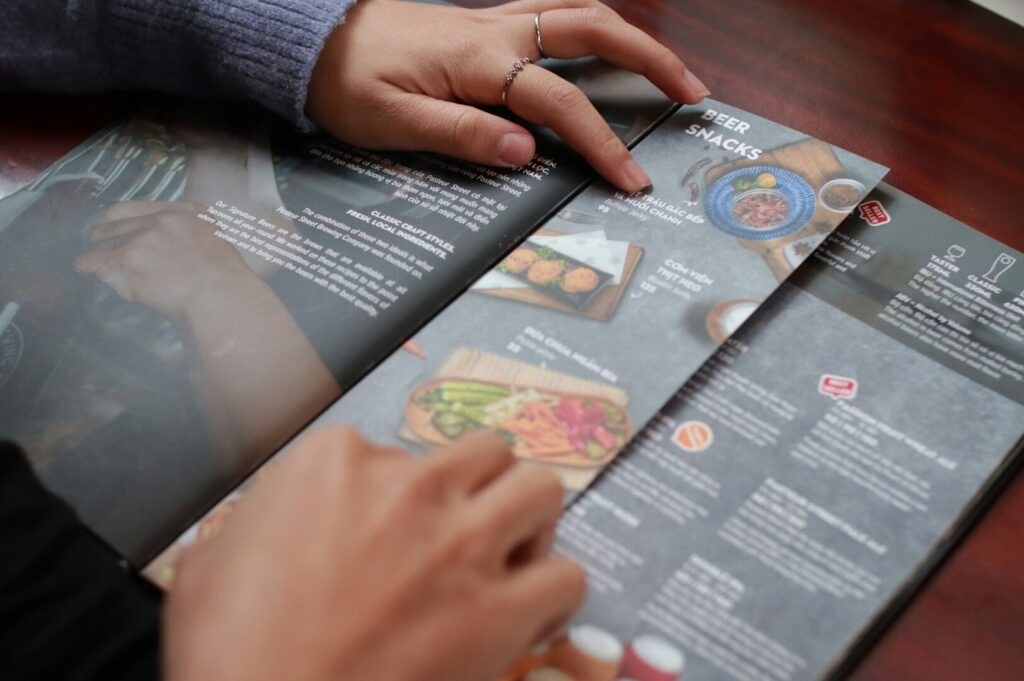A person holds a beautifully designed menu featuring various food items, showcasing food photography.
