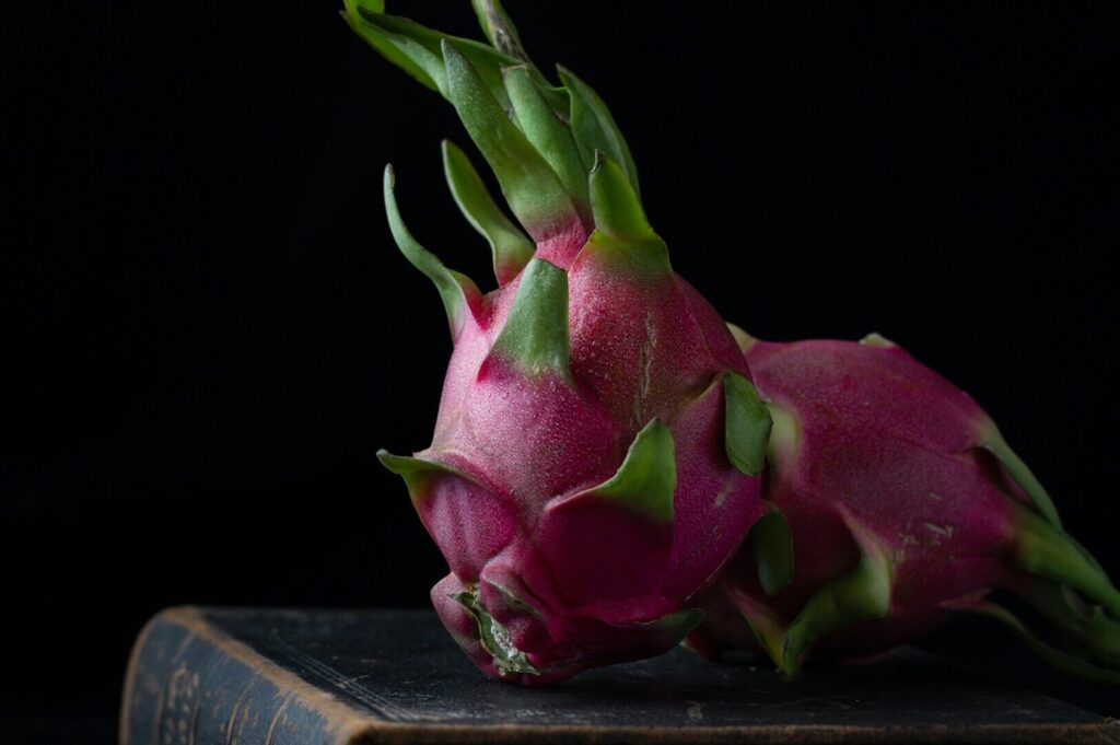 A pair of vibrant dragon fruits resting on an open book, showcasing a blend of food art and literature.