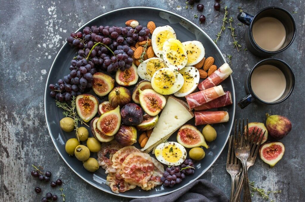 A beautifully arranged plate featuring assorted fruits, cheese, eggs, and various other foods, showcasing vibrant colors.