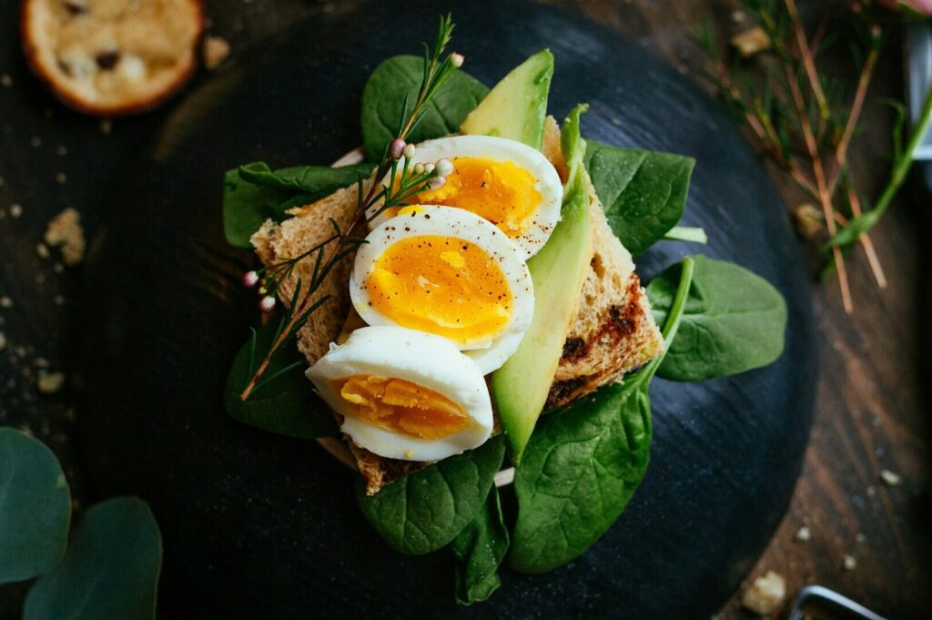 A beautifully arranged plate with an egg, creamy avocado, and fresh spinach, highlighting appetizing food photography.