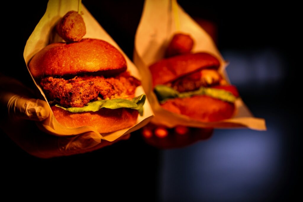 Two delicious hamburgers are prominently displayed on a black background, emphasizing their appeal in Singapore food photography.