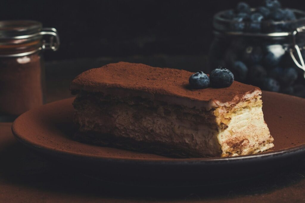 A decadent piece of chocolate cake garnished with blueberries, served on a decorative plate.