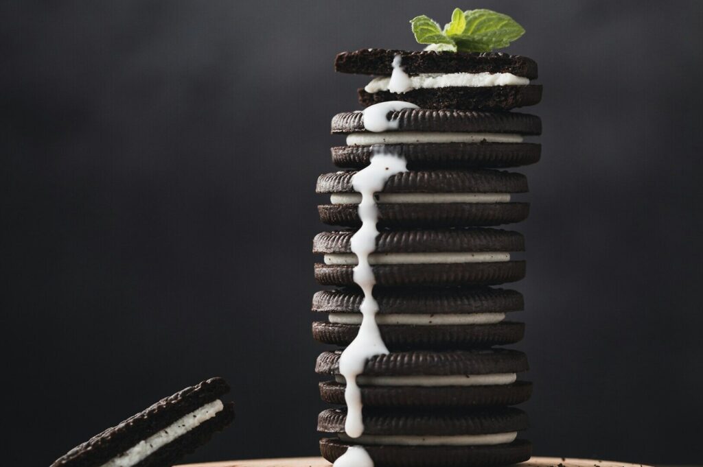 A visually appealing stack of Oreo cookies with cream, accented by vibrant mint leaves, captured in food photography.