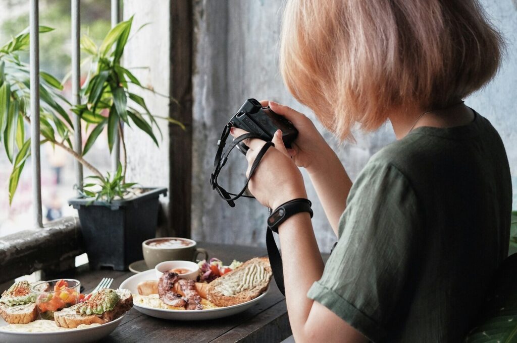 A woman photographing a beautifully arranged plate of food for food photography purposes.