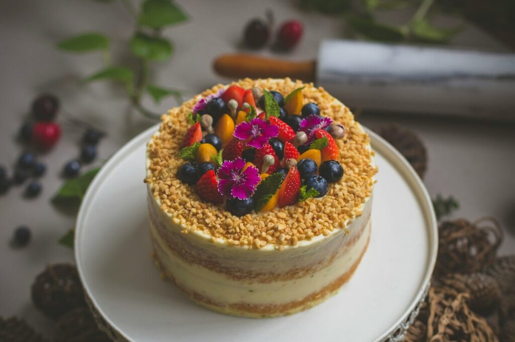 A beautifully decorated cake topped with fresh berries and nuts, showcasing vibrant colors and textures in food photography.