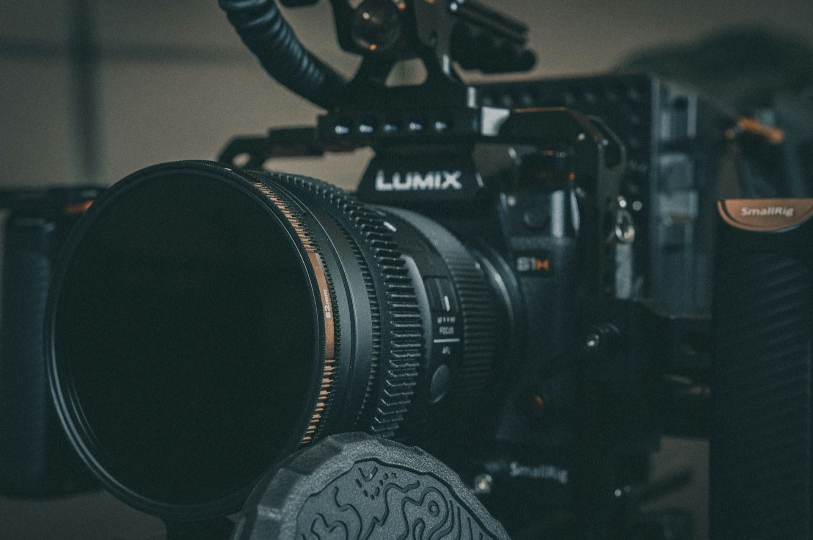 Close-up of a professional Lumix camera rigged with a cine lens and SmallRig cage. The setup conveys a focused and technical ambiance.