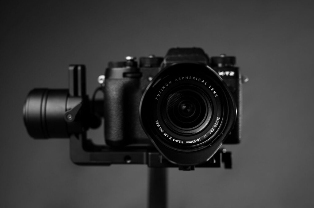 Close-up of a professional camera with an aspherical lens on a stabilizer, set against a dark, neutral background, conveying a sleek and focused tone.