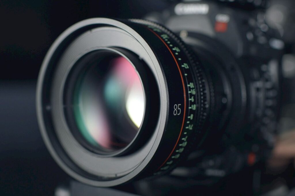 Close-up of a professional camera lens with an 85mm focal length, featuring a sleek black design and colored focus markings, conveying precision.