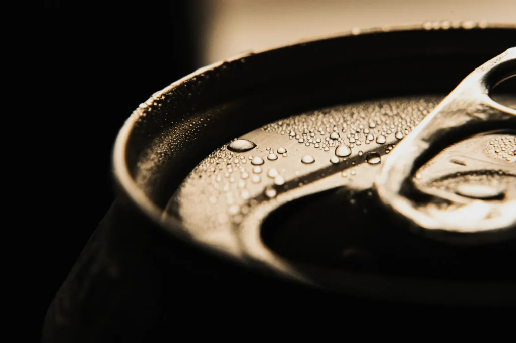 “Close-up of a beverage can's top with condensation droplets. The soft lighting and focus highlight texture and evoke a cool, refreshing feeling.”
