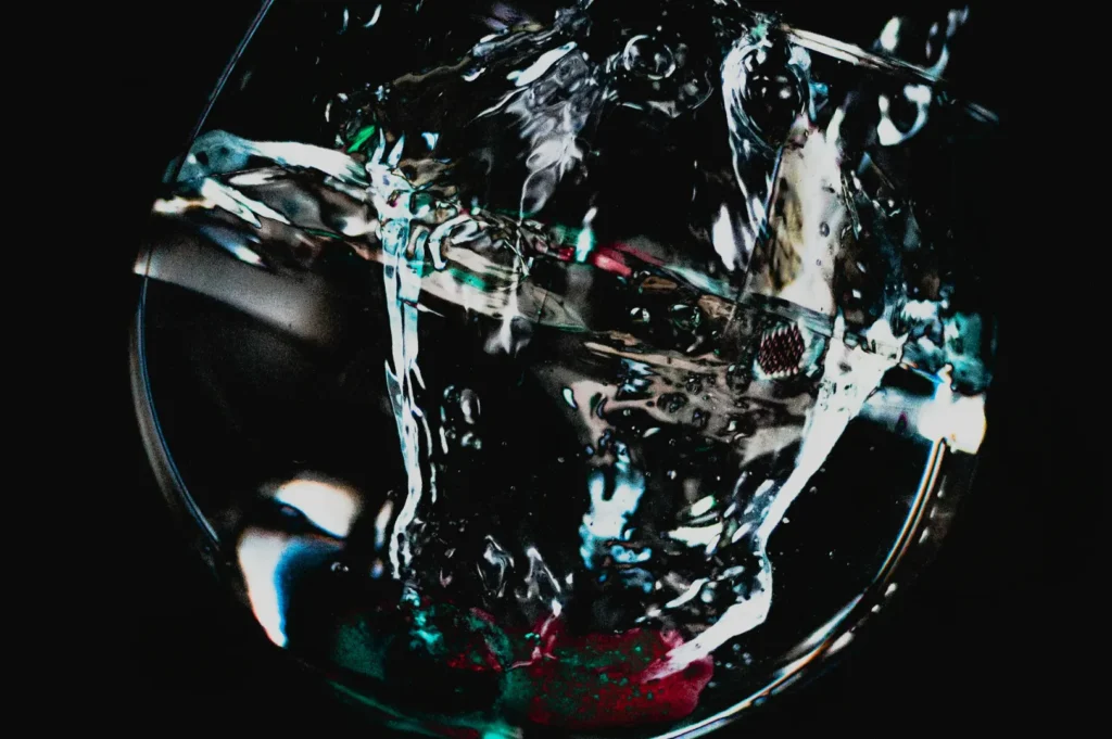 “Close-up of water splashing inside a glass against a dark background. The motion and reflections create an abstract, vibrant pattern with a dynamic feel.”