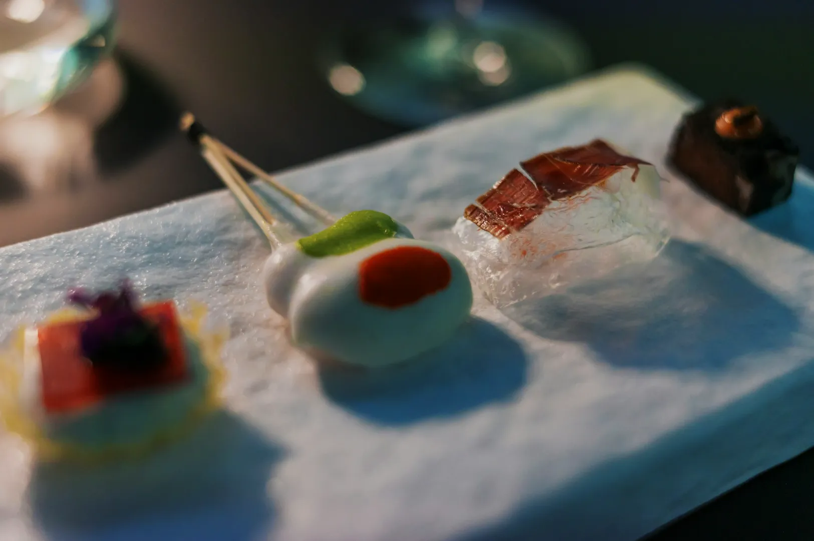 An elegant appetizer platter on a marble plate features a delicate variety of gourmet bites, artistically arranged, with a minimalist and sophisticated presentation.