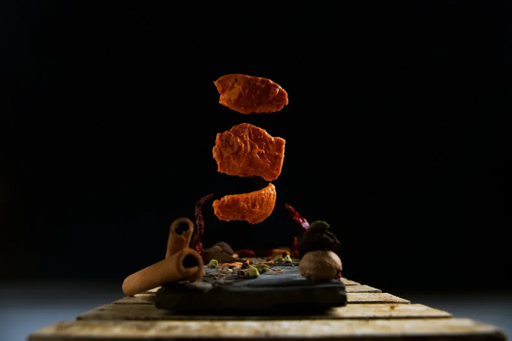Floating dried turmeric pieces hover above a rustic surface adorned with cinnamon sticks and various spices against a dark background, conveying a mystical and aromatic mood.