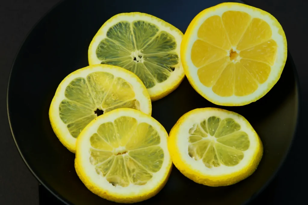 Slices of lemon arranged on a black plate. The vibrant yellow contrasts with the dark background, creating a fresh, zesty, and inviting appearance.