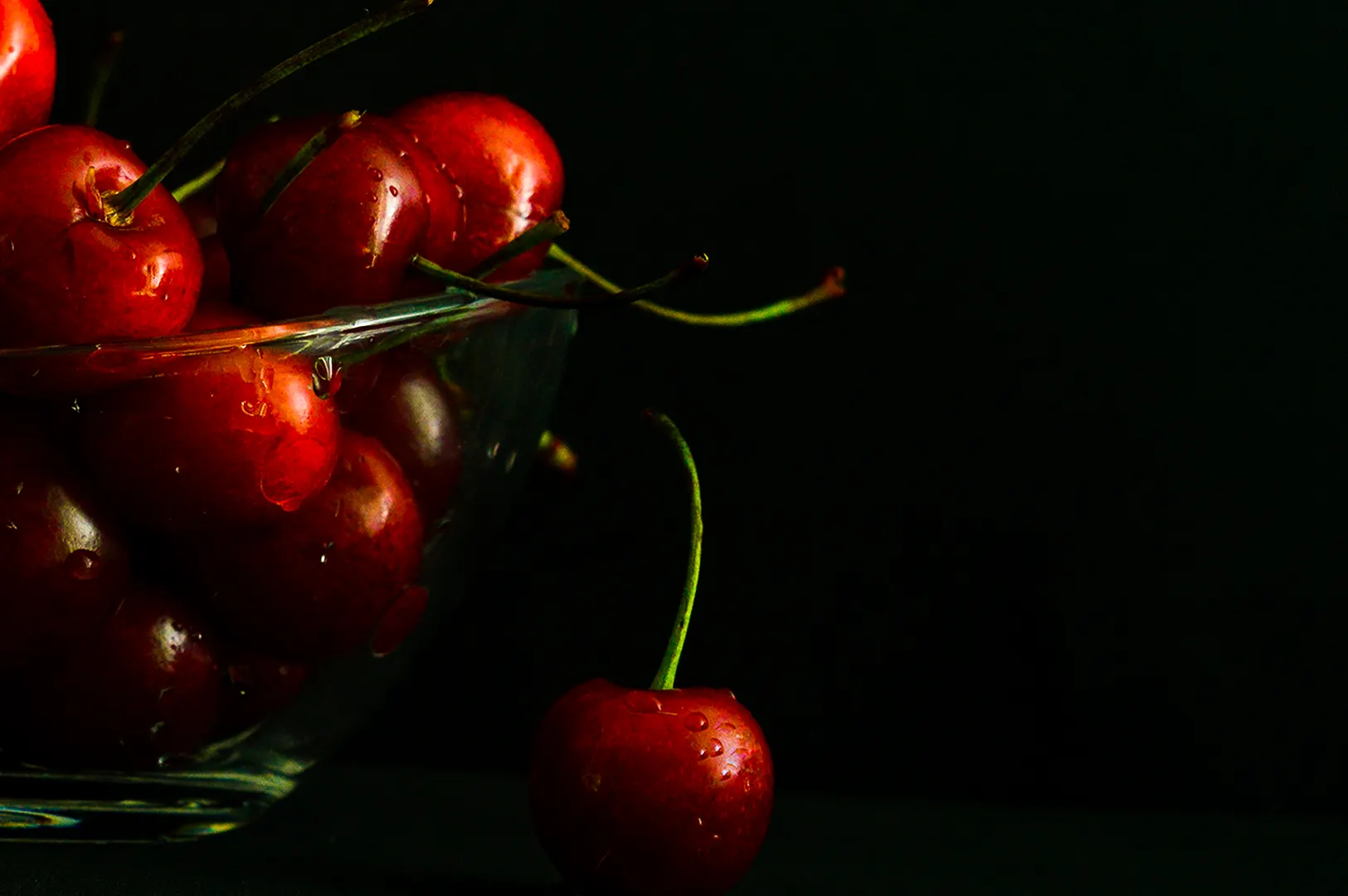 Fresh red cherries in a glass bowl on a dark background