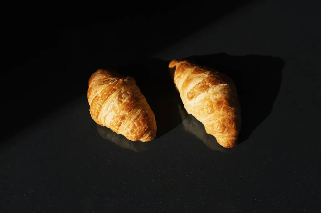 Freshly baked golden butter croissants on a dark surface.