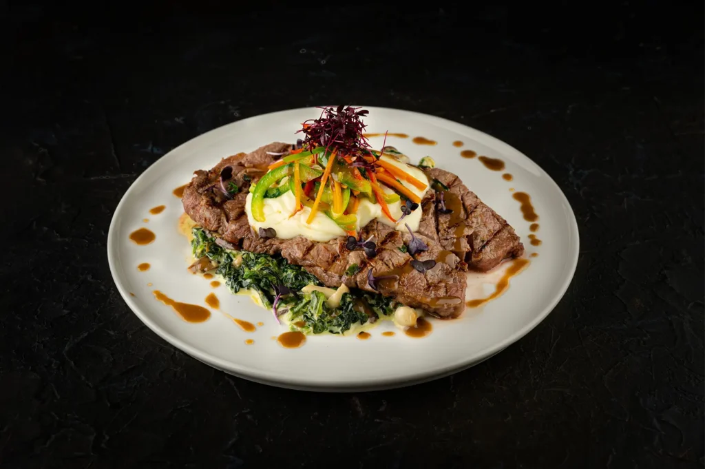 Grilled steak with mashed potatoes and vegetables on a plate.