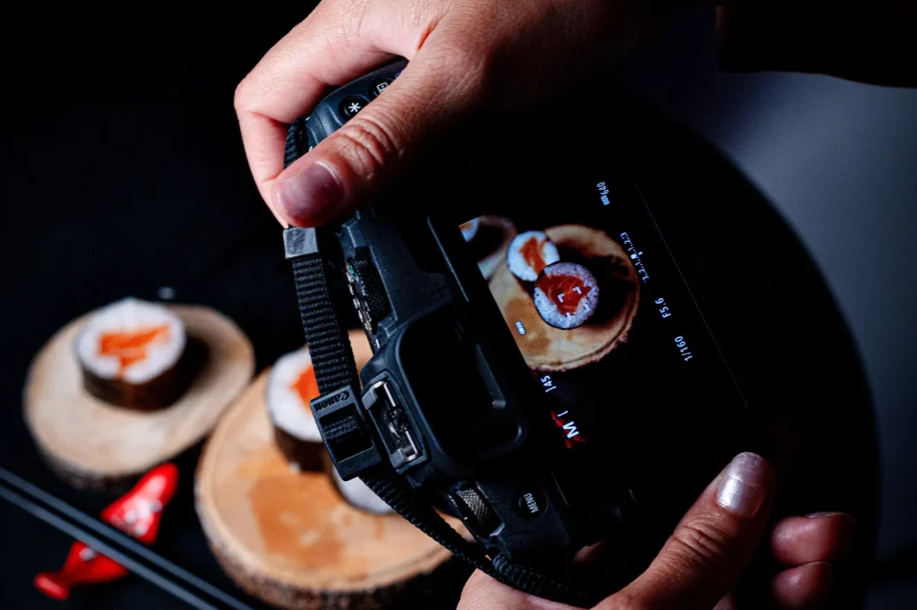 Photographer taking a picture of sushi rolls with a DSLR camera.