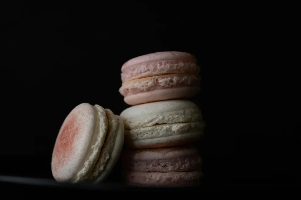 Stack of delicate pastel-colored French macarons on a black background.