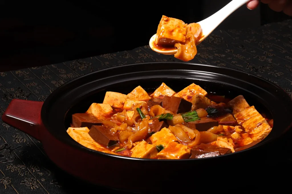 Spicy mapo tofu with cubes of tofu and blood curd served in a black pot.