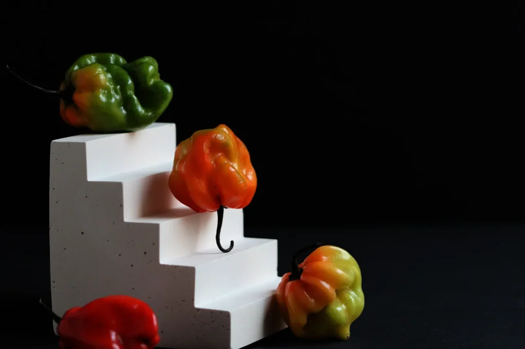 Colorful habanero peppers arranged on a three-angle white stair display against a black background.