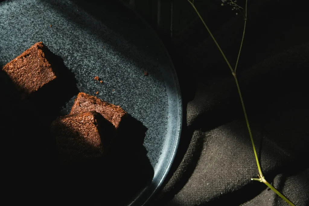 Two moist chocolate brownie squares served on a dark textured plate.