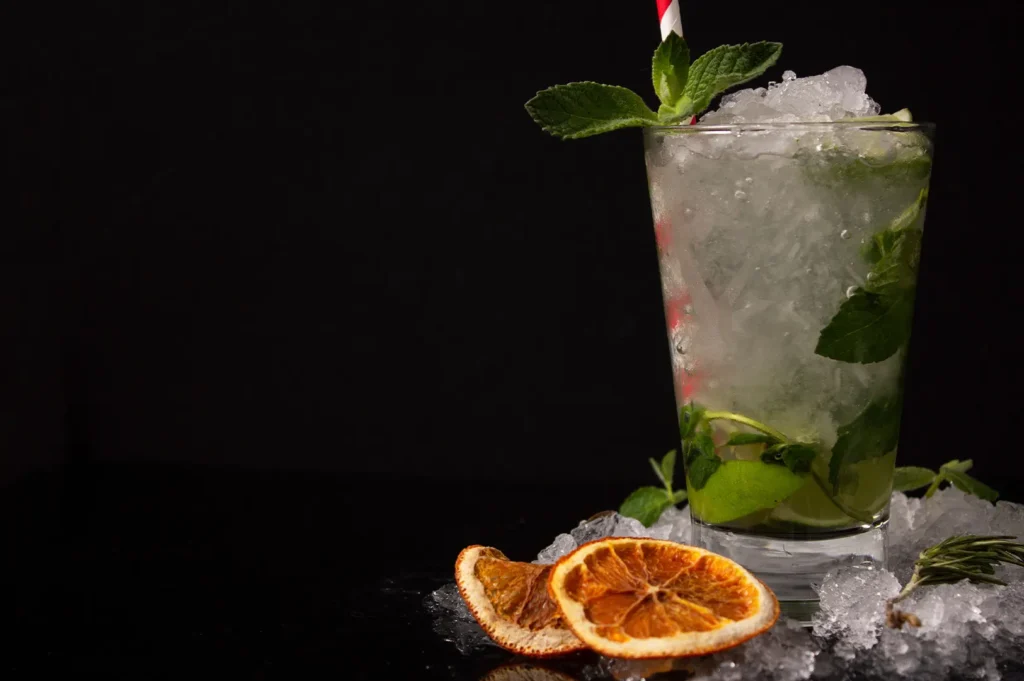 Refreshing mojito cocktail with crushed ice, fresh mint, and lime on a dark background.