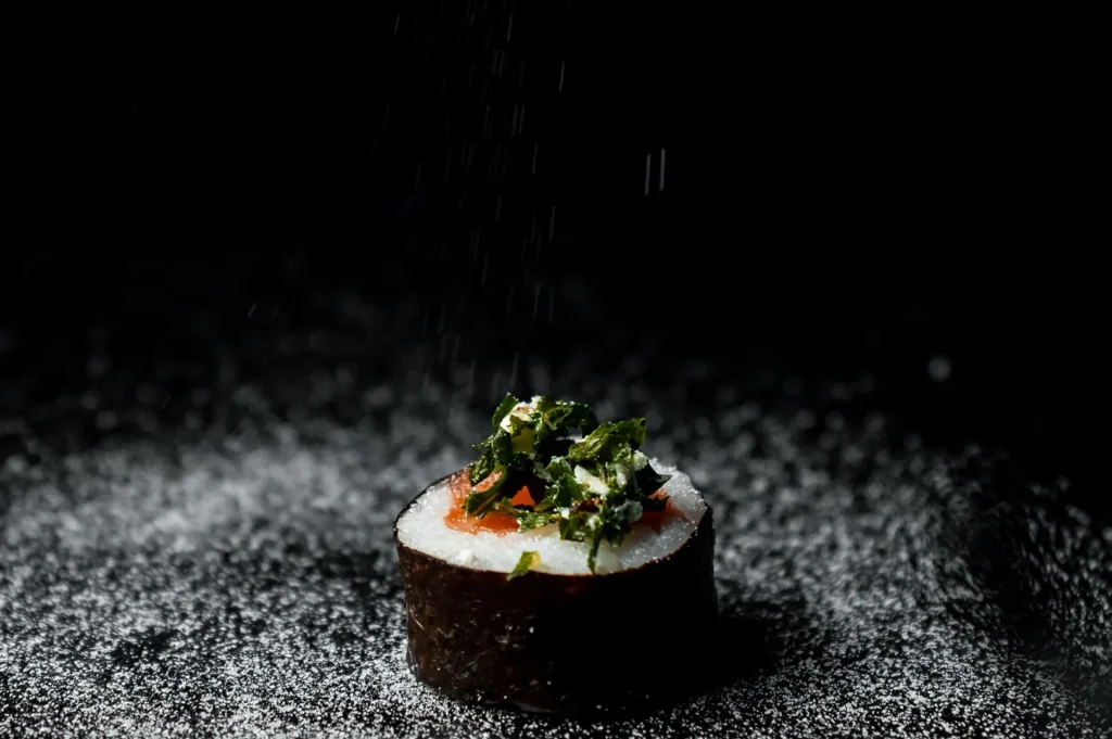 Fresh sushi roll garnished with herbs against a dark background