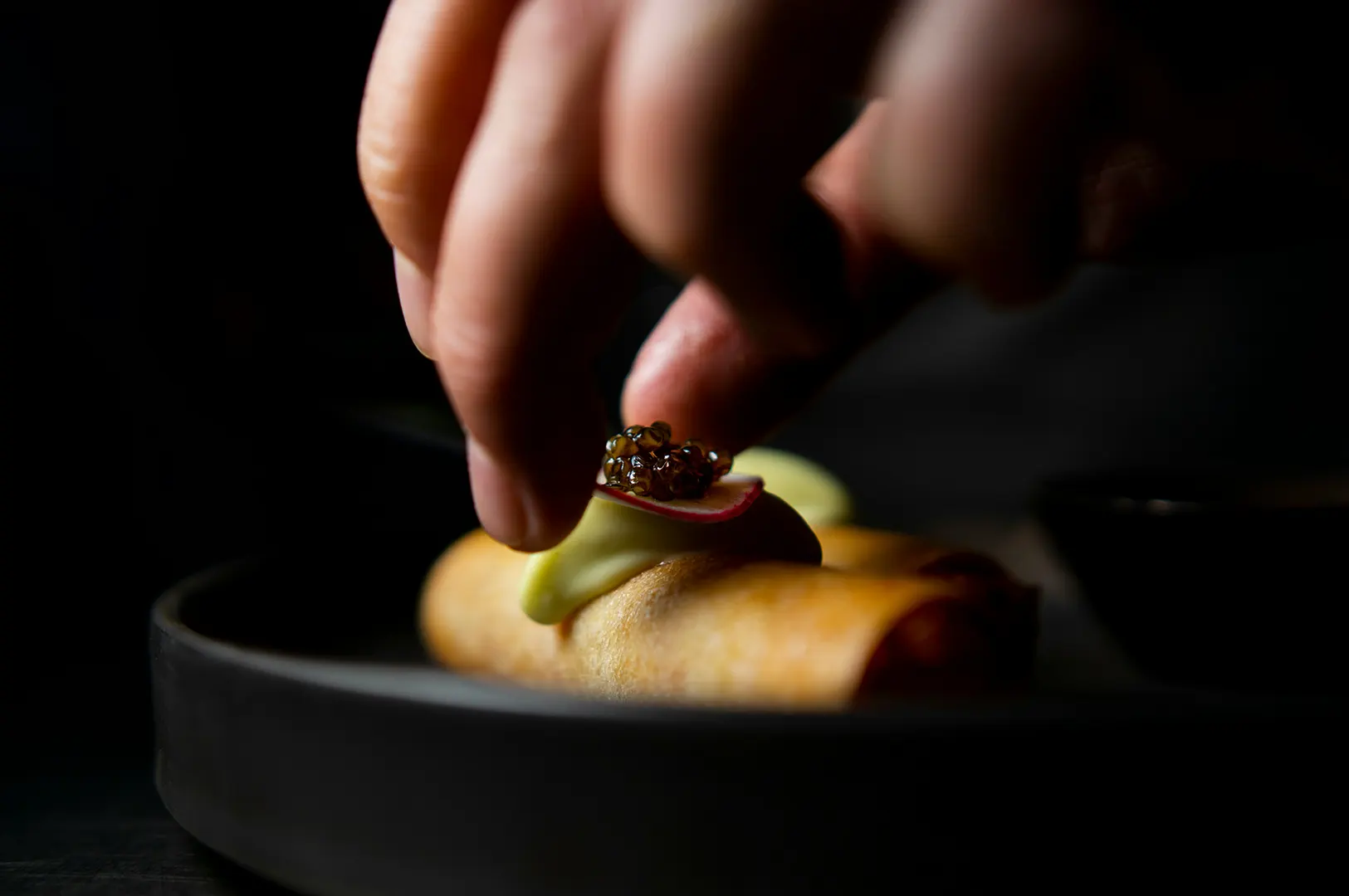 Chef plating a gourmet dish during a restaurant photo shoot.