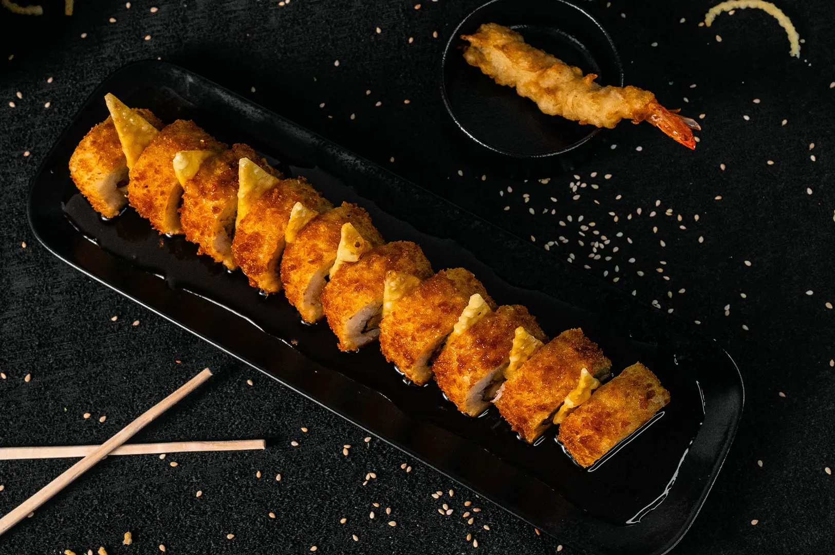 Dark moody food photography of crispy fried brown food on a black plate.