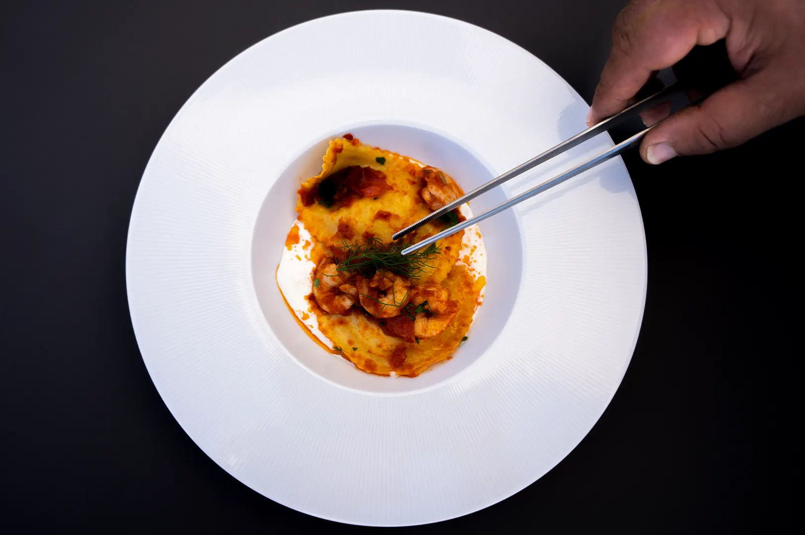 Professional food styling of a gourmet dish on a white plate with a dark background for restaurant menus and delivery apps.