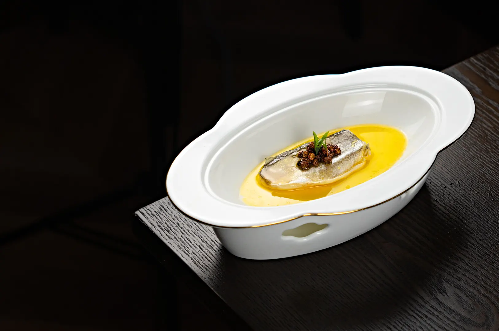 Steamed fish in a white bowl on a dark table, illustrating dark food photography for pale dishes.