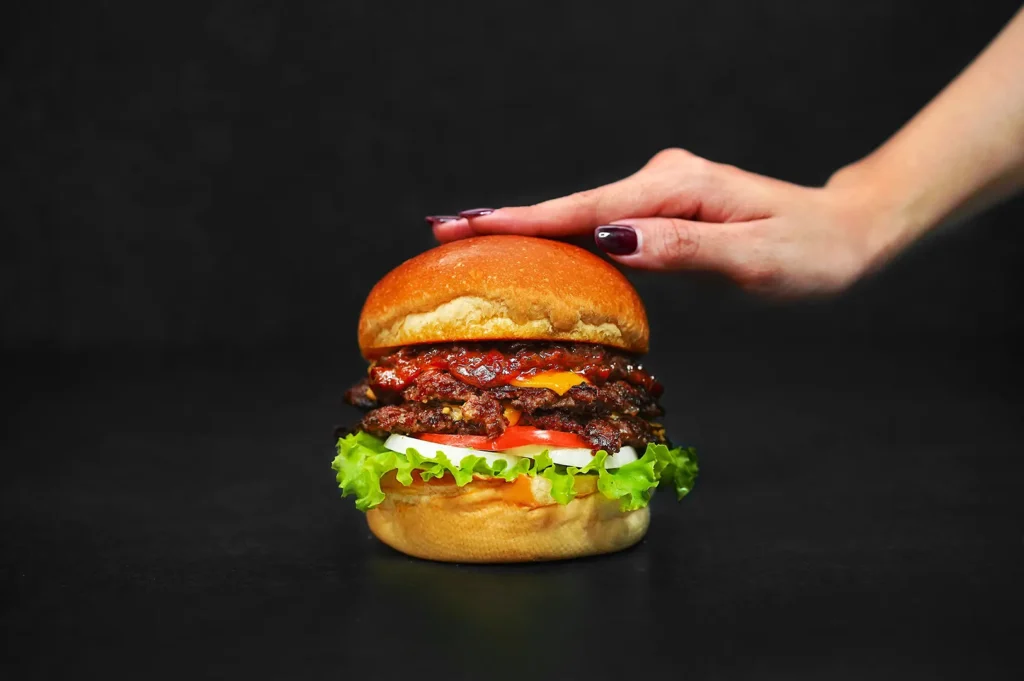 Commercial food photography of a gourmet double cheeseburger on a dark background licensed for restaurant marketing.